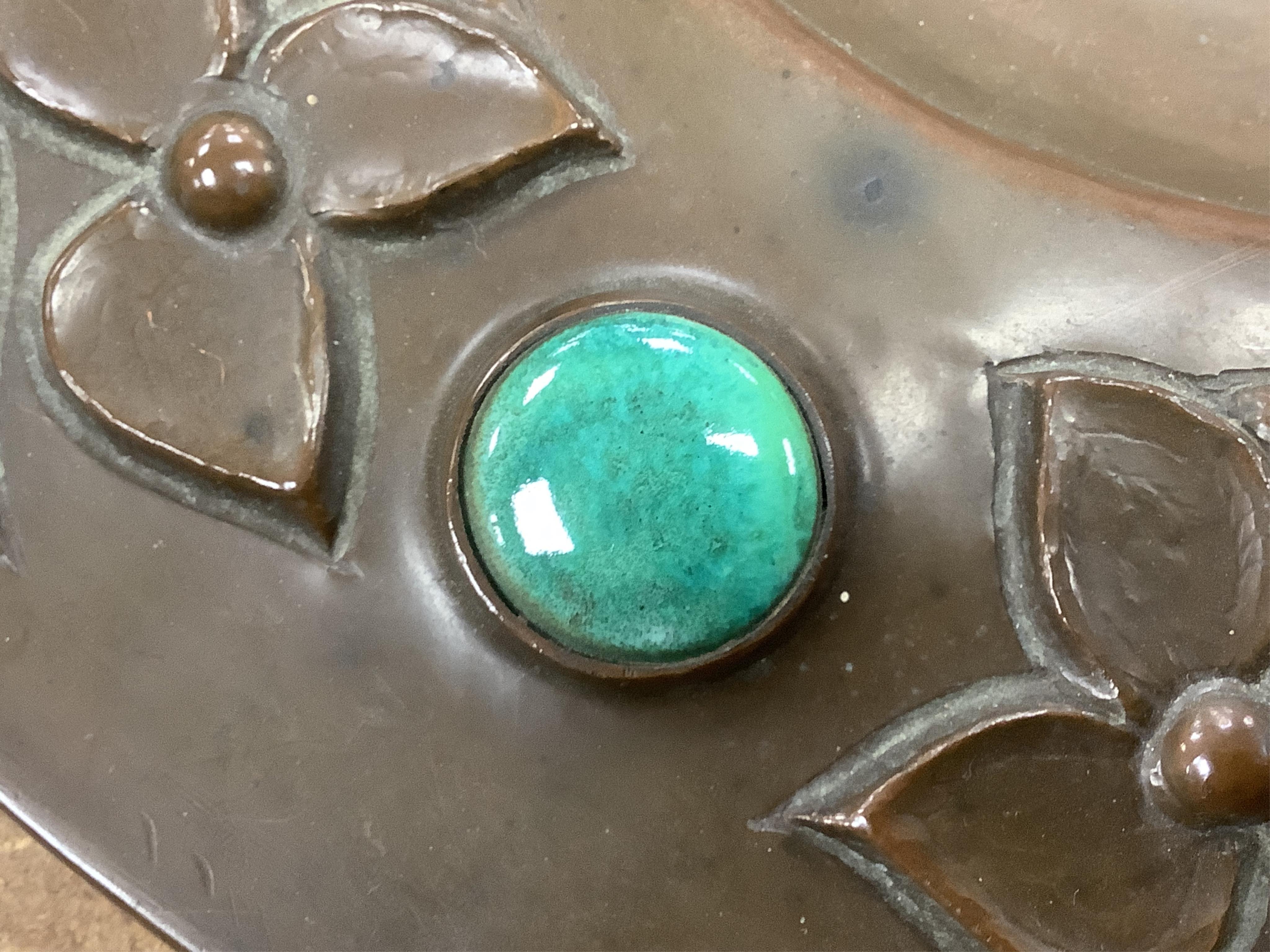 An Arts and Crafts embossed copper dish, in the manner of John Pearson, inlaid with Ruskin cabochons, unsigned, 32cm in diameter